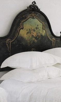 a bed with white linens and an ornate headboard