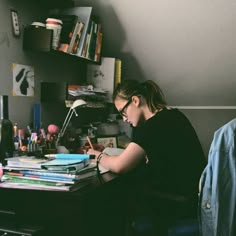 a woman sitting at a desk writing on a piece of paper