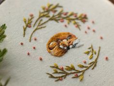 a close up of a embroidery on a piece of cloth with flowers and leaves around it