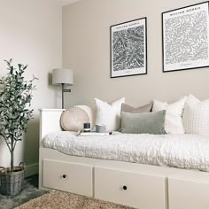 a white day bed sitting in a bedroom next to two pictures on the wall