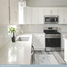 a white kitchen with stainless steel appliances and marble counter tops is pictured in this image