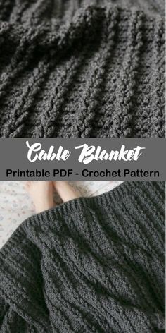 the cabled blanket is knitted in dark grey yarn