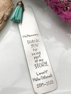 a bookmark with a tassel on top of it next to some pink flowers