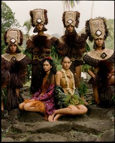 a group of women dressed in native clothing sitting next to each other on some rocks