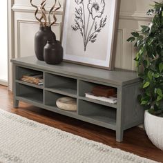 a gray shelf with two vases and a framed flower print on it next to a white rug