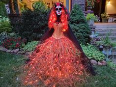 a woman dressed up in a skeleton costume with lights on her head and dress is standing outside