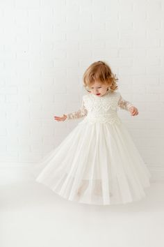 "This stunning dress is a beautiful vintage inspired look...perfect for any little girl and occasion! This dress has a boho flair and a super feminine feel. It is made in gorgeous crochet bodice lace and long sleeves, ankle length tulle skirt made of heavenly layers. Nicolette's Couture is a family owned boutique based out of Dubuque, Iowa. When creating looks, comfort is our main priority...regardless of how chic a style is. We've had amazing success so far and believe our story is just beginni Cream Fitted Princess Dress For Wedding, Cream Princess Dress For First Communion, Cream Princess Tutu Dress For First Communion, Elegant Cream Princess Dress With Tulle Skirt, First Communion Ball Gown With Tulle Skirt For Baptism, Lace Tulle Gown For First Communion, Cream Gown With Lace Bodice And Tulle, Cream Gown With Lace Bodice And Tulle Material, Fitted Cream Princess Dress For First Communion