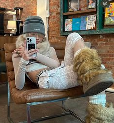 a woman is sitting on a chair with her legs crossed and holding a cell phone