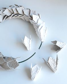 several pieces of paper are arranged in the shape of an origami wreath on a white surface