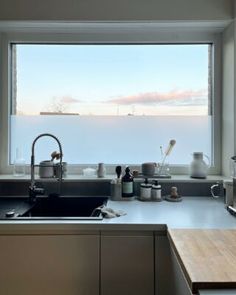 a kitchen with an open window overlooking the water and sky is pictured in this image