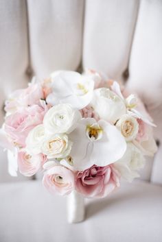 a bridal bouquet sitting on top of a white chair with pink and white flowers