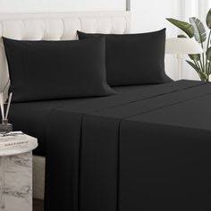 a bed with black sheets and pillows on it