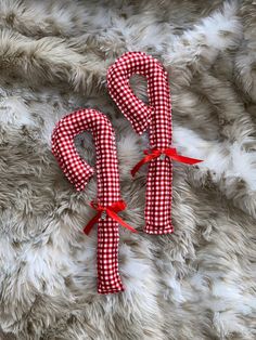 two red and white checkered candy canes laying on top of a furry surface