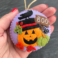 a hand holding a small ornament with a pumpkin on it