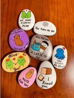 five rocks with different designs on them sitting on a wooden table next to each other