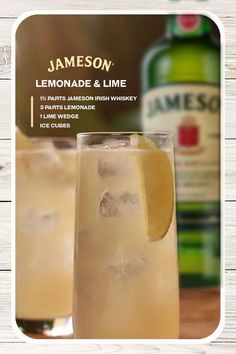 a glass filled with lemonade and lime next to a bottle of jameson on a wooden table