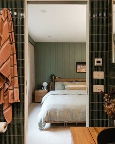 a bed sitting in a bedroom next to a bathroom with green tile on the walls