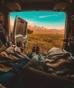 a person laying in the back of a truck with their feet up on a blanket