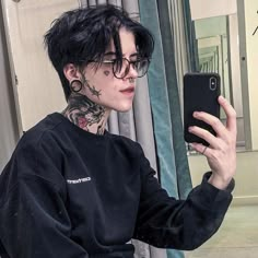 a young man with black hair and tattoos taking a selfie in front of a mirror