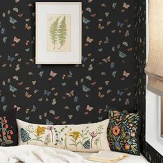 a bedroom with black wallpaper and colorful butterflies on the wall next to a bed