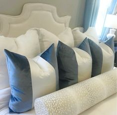 four pillows are lined up on a bed with white sheets and blue pillow cases in front of the headboard