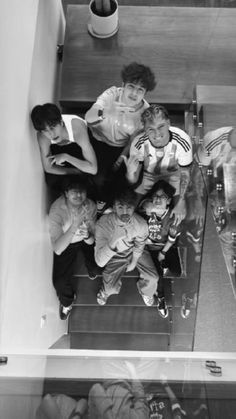 black and white photograph of people sitting on stairs with one person taking a photo in the mirror