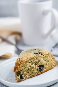 a close up of a piece of cake on a plate with a cup in the background