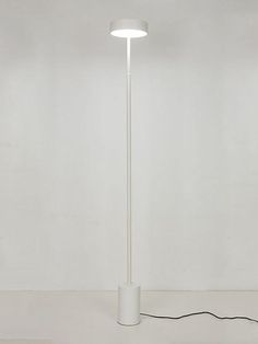 a white floor lamp with a cord plugged in to the base and a light on top