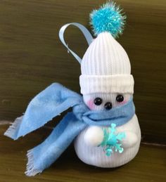 a small stuffed animal with a blue scarf and hat on it's head sitting on a table