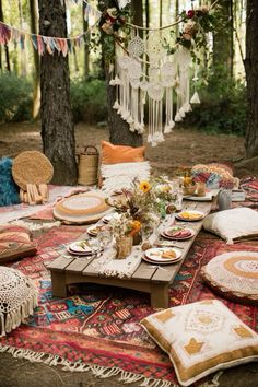 an outdoor picnic is set up in the woods with pillows, plates and other items