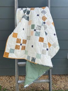 a chair with a quilt on it sitting in front of a wall next to a ladder