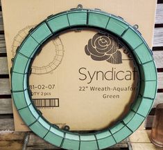 a green round frame sitting on top of a wooden pallet next to a box