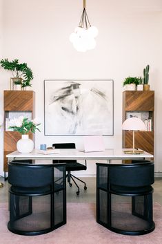 a desk with two chairs and a painting on the wall