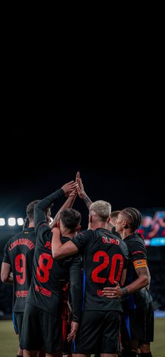 a group of people standing on top of a soccer field holding hands in the air