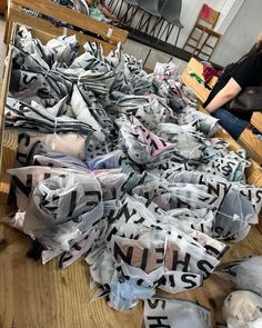 a pile of clothes sitting on top of a wooden floor next to a woman in a black shirt