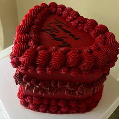 a heart shaped red cake sitting on top of a white table