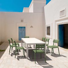 a white table and chairs sitting on top of a stone floor next to a building