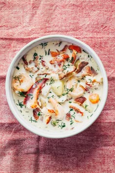 a white bowl filled with seafood chowder on top of a red cloth