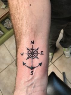 a man with a compass tattoo on his arm