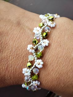 a woman's arm wearing a bracelet with flowers and pearls on the clasps