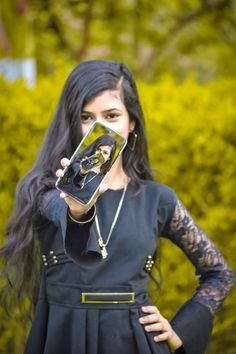 a woman with long black hair holding up a cell phone