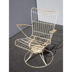 a white metal chair sitting on top of a black floor next to a gray wall