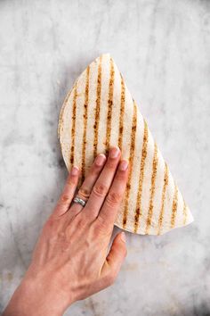 a person holding a tortilla on top of a marble counter