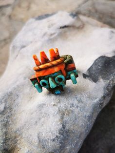 an orange and blue ring sitting on top of a rock