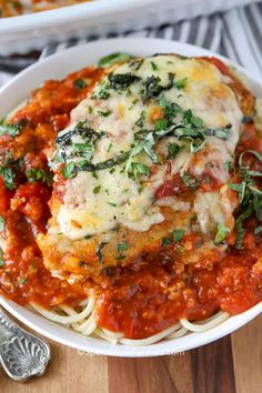 a white bowl filled with pasta covered in sauce and parmesan cheese on top