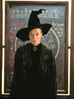 an older woman wearing a witches hat in front of a chalkboard