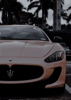 a masera parked in a parking lot next to palm trees