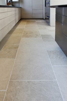 an empty kitchen with tile flooring and stainless steel appliances in the back ground area