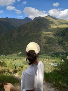 a woman standing on top of a lush green hillside