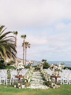 an outdoor wedding setup with white flowers and greenery on the lawn next to the ocean